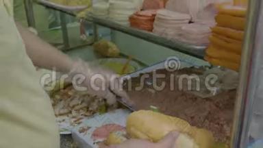 一个小贩把肉放进面包里做三明治